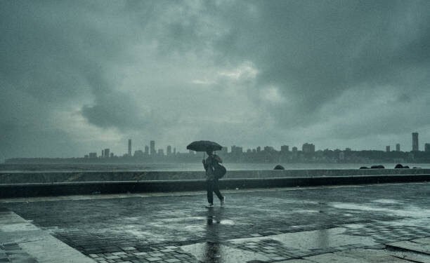 A man walks alone the Marine Drive as the Monsoon Clouds take over the Mumbai coastline.